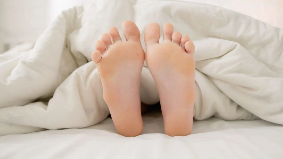 따뜻한 조명 아래 담요를 덮고 쉬는 다리와 발